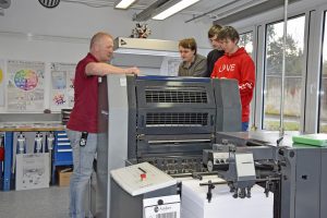 Auszubildende und Ausbilder vor der neuen Druckmaschine in der BvB