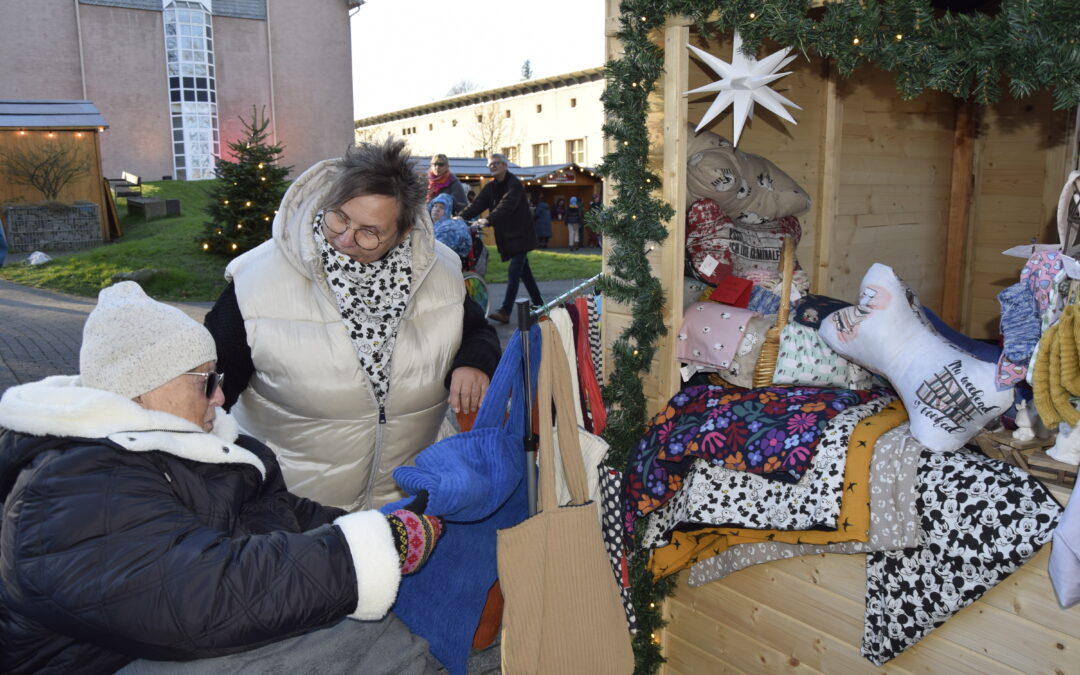 Zwei Frauen betrachten die Produkte an einem Stand auf dem Adventsmarkt.