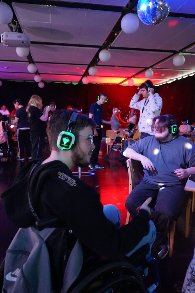 Gäste der Silent-Disco sitzen am Rand und hören Musik über die Kopfhörer.